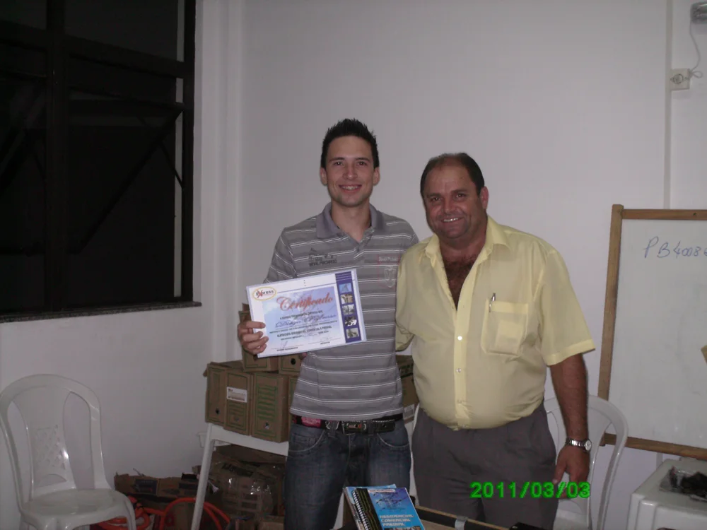 Claudio Moraes ao lado de um aluno com certificado, em registro de sua trajetória no ensino de elétrica